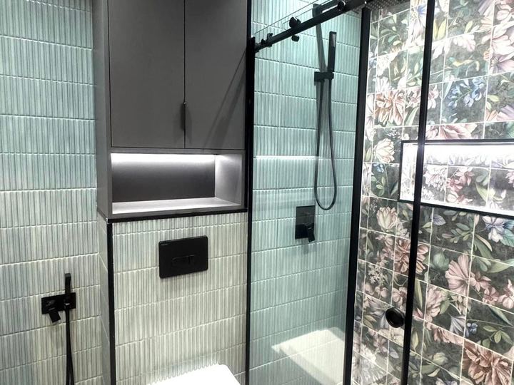 Green tile shower with black fixtures, a lit niche and a floral tile wall - Sani Building Corp