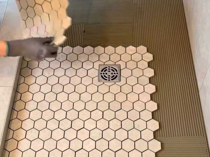 Hexagon mosaic tile being set on a shower floor around the drain - Sani Building Corp