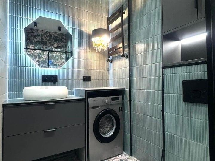 Bathroom with green vertical tile, a backlit mirror and a washer under the counter - Sani Building Corp