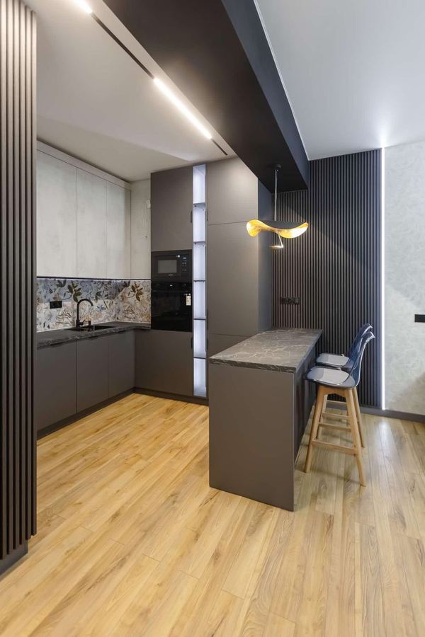 Peninsula and Oven Tower - Matte cabinets, stone breakfast bar, lit open shelves - Sani Building Corp