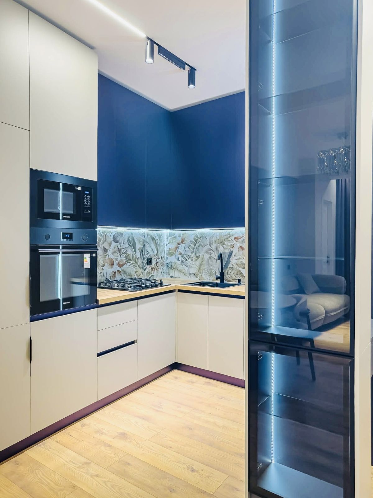 Finished modern kitchen with tall cabinets and a lit glass display cabinet - cabinet installation by Sani Building Corp