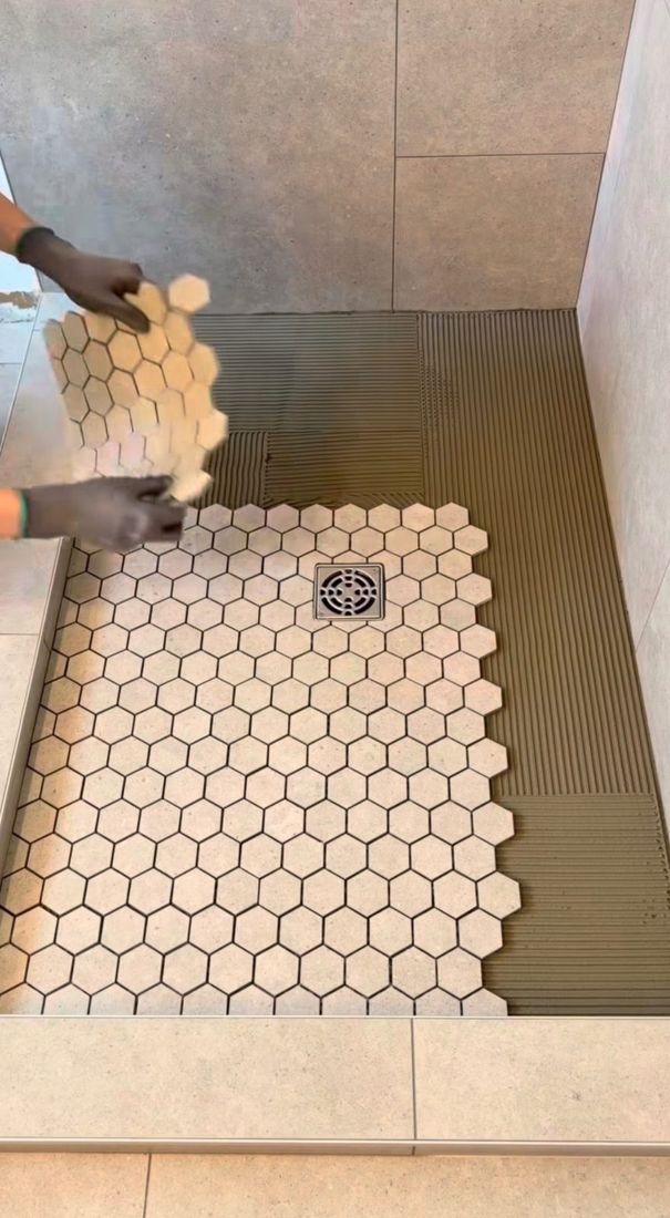 New shower pan being tiled with hexagon mosaic after replacement in NYC